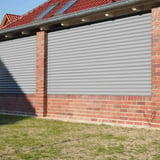 Golfplaat 18/1064, lichtgrijs, als wandbekleding tussen rode bakstenen pilaren van een gebouw