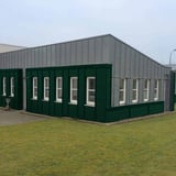 Golfplaat 18/1064 mosgroen als gevelbekleding op een modern gebouw met veel ramen
