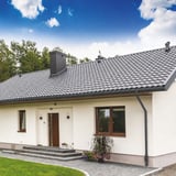 Rinnenuitloop grafietgrijs (RAL 7024) op een wit huis met donker dakpannen dak