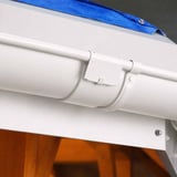 Gemonteerde zuiverwitte dakgootverbinder met dakgoot aan een dakrand
