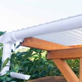 Witte PVC dakgoot met regenpijp en console dakgootbeugels aan een houten constructie