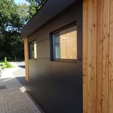Zijaanzicht van een gebouw met donkere HPL platen en houten bekleding