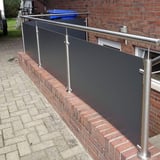 Balkonborstwering van donkere HPL platen en RVS balustrade op een bakstenen muur