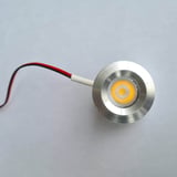 Een LED verlichting extra spot, blank aluminium, met zwarte en rode kabel, ingeschakeld