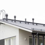 Donkergrijs Weckman looprooster op een dak met dakpannen en ventilatiepijpen, verlegd