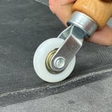 Close-up van het witte nylon wiel van de hoekroller tijdens het aandrukken op donkere ondergrond