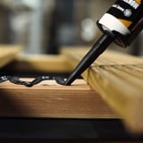 Montagelijm Turbo zwart wordt op een houten constructie aangebracht, detail van de lijmrups