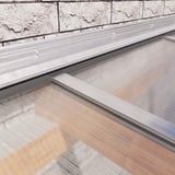 Wandaansluitprofiel van blank aluminium, gemonteerd aan een bakstenen muur boven lichtplaten