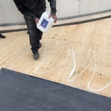 DACHPROTECT BlueTek oppervlakte lijm wordt uit de jerrycan in witte banen op houten dak gegoten