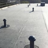 Meerdere zwarte EPDM buismanschetten op een plat dak met ontluchtingsbuizen