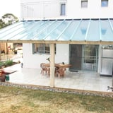 Terrasoverkapping met heldere polycarbonaat lichtplaten aan een wit huis