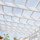 Gelegde heldere polycarbonaat golfplaten 76/18 als terrasoverkapping met bloemen en zonnebloemen