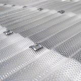 Close-up van de bevestiging van een heldere polycarbonaat golfplaat 76/18 met schroef en kalot