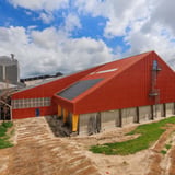 Groot industrieel gebouw met terracotta golfplaten dak en gevel