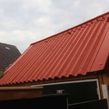 Terracotta golfplaten dak met schroeven op een tuinhuis of afdak