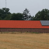 Groot gebouw met terracotta golfplaten dak en zonnepanelen