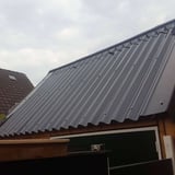 Donkergrijze golfplaten van Stabipol op een schuin dak, gemonteerd met schroeven