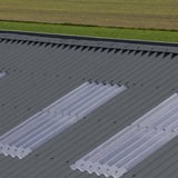 Detail van donkergrijze golfplaten met lichtplaten op een dak, verlegd