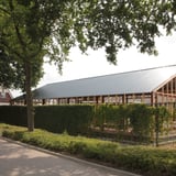Donkergrijze golfplaten op een langgerekt gebouw met houten constructie, verlegd als dak