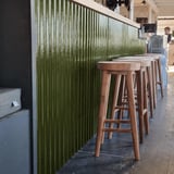 Groene golfplaten van polyester, 0,85 mm dik, als decoratieve wandbekleding achter een bar met krukken