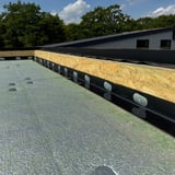 Randfixatiestrip EPDM zwart gemonteerd op houten onderconstructie van een plat dak