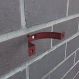 Kersrode valbuisklem van staal gemonteerd op een bakstenen muur, zonder valbuis