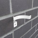 Enkele zuiverwitte (RAL 9010) regenpijpbeugel van staal gemonteerd op een donkere bakstenen muur