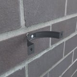 Grafietgrijze valbuisklem van staal, gemonteerd op een bakstenen muur, zonder valbuis