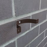Chocoladebruine regenpijpbeugel van staal gemonteerd op een bakstenen muur, detail