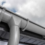 Detail van een grijs aluminiumkleurige Niagara regenpijpbocht met waterdruppels op het oppervlak