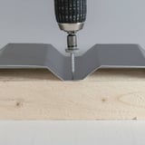 Montage van een RVS schroef met boormachine in damwandplaat op hout, schroef aangezet