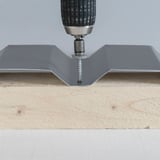 RVS schroef wordt met boormachine in diepte van een grijze damwandplaat op hout geschroefd