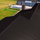 Dakoverzicht met sandwichpanelen ECO 1000-30 in grijsbruin (RAL 8019) en groene omgeving
