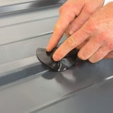 Handen drukken een zwarte EPDM schroef reparatiepleister op een profielplaat