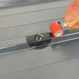 Hand rolt met een rode roller over een zwarte EPDM schroef reparatiepleister op profielplaat