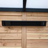 Verwarming aluminium zwart, gemonteerd aan houten wand, direct vooraanzicht