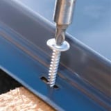 Verzinkte schroef wordt met bit in felsplaat op houten onderconstructie geschroefd