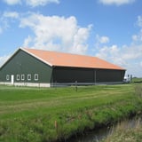 Grote schuur met vezelcement golfplaten 6,00 mm terracotta op het dak, verlegd