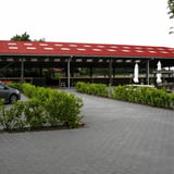 Vezelcement golfplaten 6,00 mm terracotta op het dak van een open loods met parkeerplaats