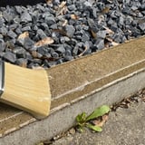 Transparant vloeibaar kunststof wordt met kwast op betonrand met grind aangebracht