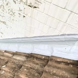 Witte vloeibare kunststof afdichting tussen dakpannen en witte muur