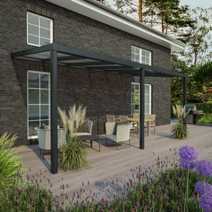 Terrasoverkapping RAL 7016 met 8,00 mm glazen dak aan een huis met donkere bakstenen muur