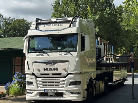 MAN-LKW levert dakplaten â expeditieverzending Witte MAN-vrachtwagen met dakplaten bij levering â voorbeeld van een transportvoertuig.