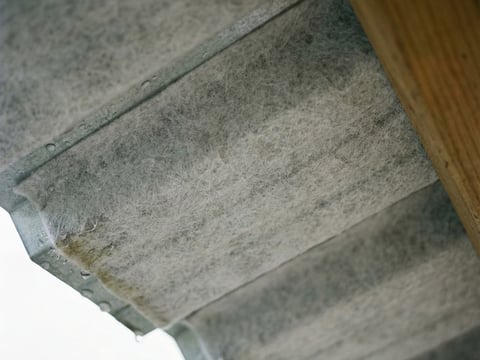 Close-up van de onderkant van een damwandplaat met grijze vliesbekleding voor carports