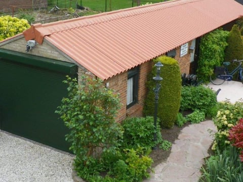 Nieuw gelegd dak met rode vezelcement golfplaten, bouwplaats op de voorgrond