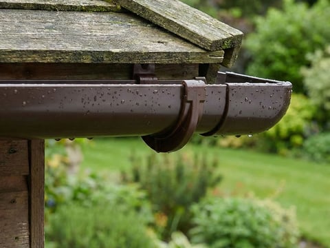 Bruine PVC-dakgoot perfect achteraf gemonteerd op een klein tuinhuisje