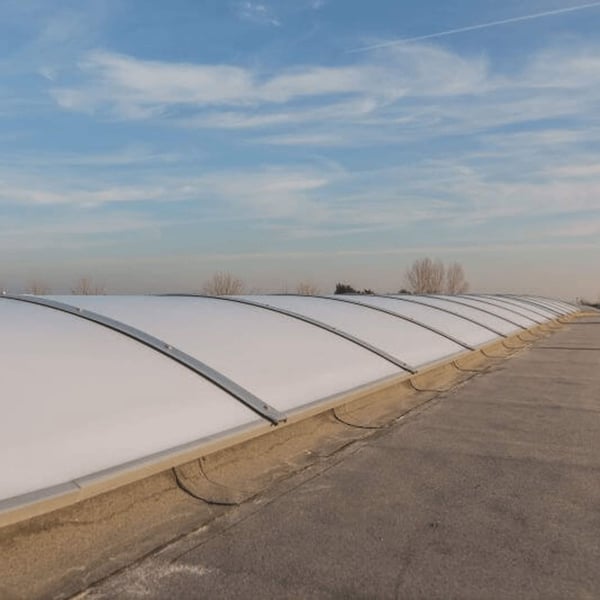 Rij Alumon lichtkoepels op een plat dak onder een blauwe lucht
