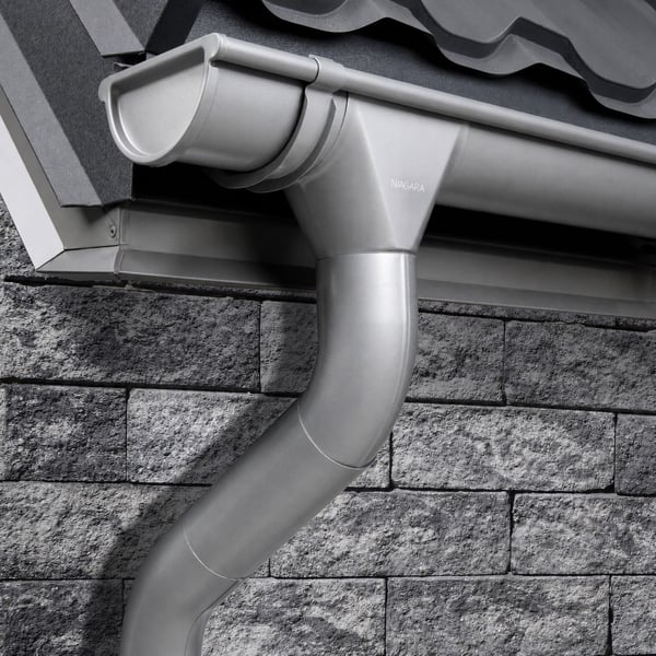 Niagara dakgoot en regenpijp in grijs aluminiumkleurig (RAL9007) gemonteerd aan een dak en muur