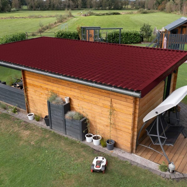 Dakpanplaat Wijnrood (RAL 3005) op het dak van een aanbouw, installatie in een tuinlandschap