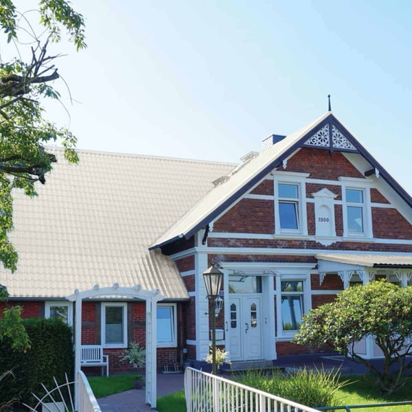 Dakpanplaat Grijswit op het dak van een historisch bakstenen huis met witte accenten